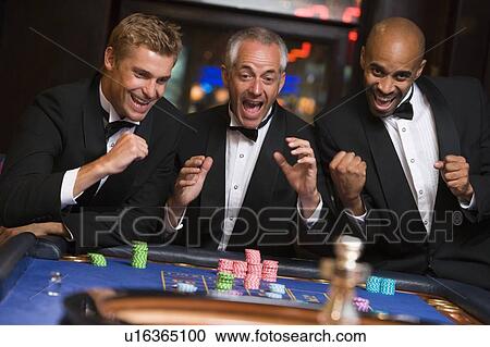 Three men in casino playing roulette smiling (selective focus) View Large Photo Image Stock Image - Three men in casino playing roulette smiling (selective focus). Fotosearch