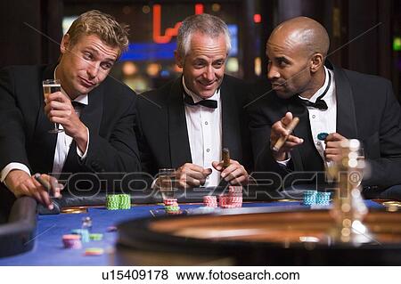 Three men in casino playing roulette and smiling (selective focus) View Large Photo Image Stock Photo - Three men in casino playing roulette and smiling (selective focus). Fotosearch