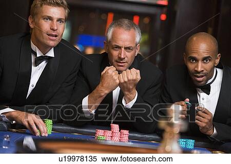 Stock Photography - Three men in casino playing roulette (selective focus). Fotosearch