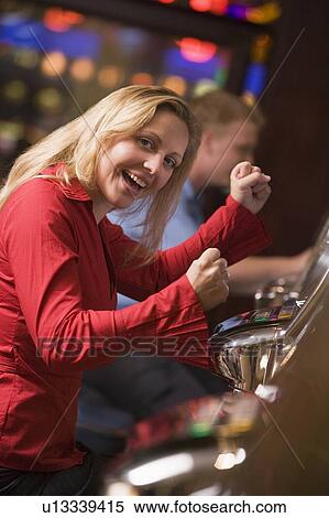Woman in casino excited playing slot machine with people in background (selective focus) View Large Photo Image Stock Photography - Woman in casino excited playing slot machine with people in background (selective focus). Fotosearch