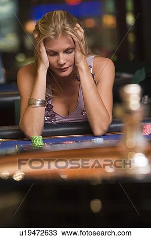 Stock Image - Woman in casino playing roulette and losing (selective focus). Fotosearch