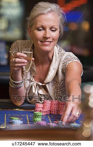 Stock Photo - Woman in casino playing roulette and smiling (selective focus). Fotosearch