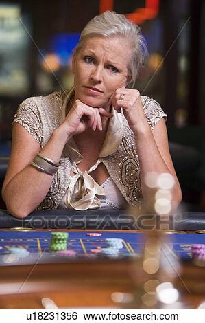 Stock Photograph - Woman in casino playing roulette and thinking (selective focus). Fotosearch