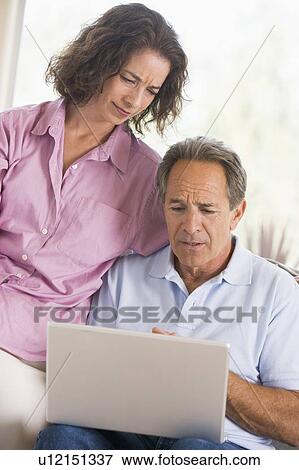 Couple in living room with laptop View Large Photo Image Stock Photo - Couple in living room with laptop. Fotosearch