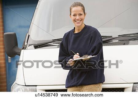 Deliveryperson standing with van writing in clipboard smiling View Large Photo Image Stock Photo - Deliveryperson standing with van writing in clipboard smiling. Fotosearch