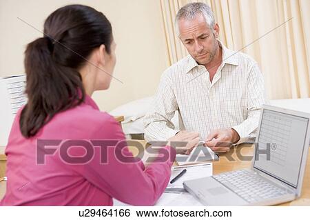 Doctor with laptop and man in doctor's office frowning View Large Photo Image Stock Photograph - Doctor with laptop and man in doctor's office frowning. Fotosearch