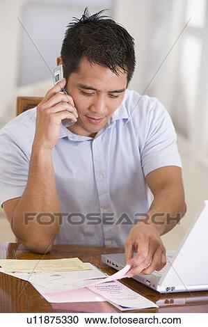 Man in dining room on cellular phone using laptop View Large Photo Image Stock Image - Man in dining room on cellular phone using laptop. Fotosearch