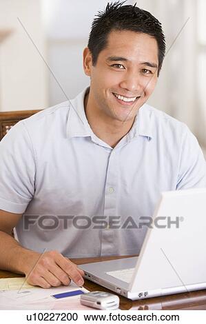 Man in dining room using laptop smiling View Large Photo Image Stock Image - Man in dining room using laptop smiling. Fotosearch