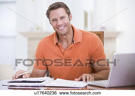 Man in dining room with laptop smiling View Large Photo Image Stock Photograph - Man in dining room with laptop smiling. Fotosearch