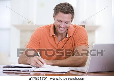 Man in dining room with laptop writing and smiling View Large Photo Image Stock Image - Man in dining room with laptop writing and smiling. Fotosearch