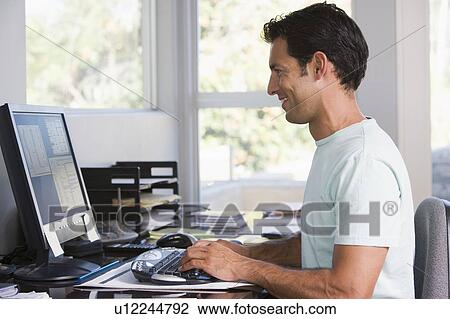 Man in home office using computer and smiling View Large Photo Image Stock Image - Man in home office using computer and smiling. Fotosearch