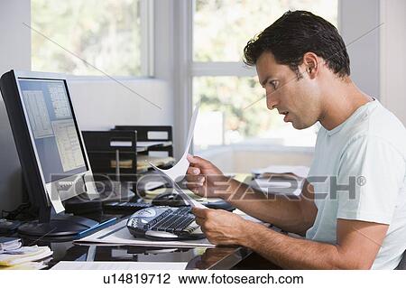 Man in home office using computer holding paperwork and looking shocked View Large Photo Image Stock Image - Man in home office using computer holding paperwork and looking shocked. Fotosearch