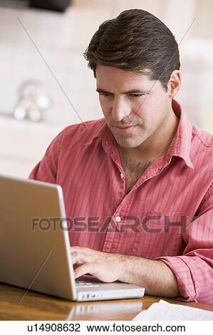 Man in kitchen using laptop View Large Photo Image Stock Image - Man in kitchen using laptop. Fotosearch