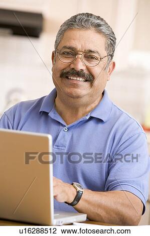 Man in kitchen with laptop smiling View Large Photo Image Stock Image - Man in kitchen with laptop smiling. Fotosearch