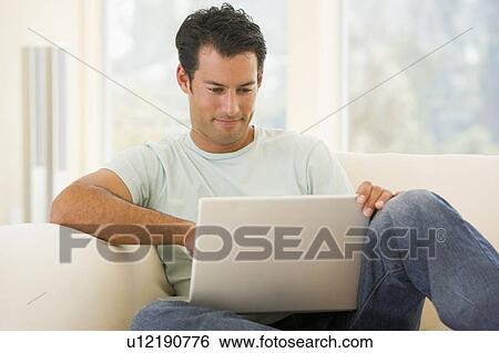 Man in living room using laptop View Large Photo Image Stock Photograph - Man in living room using laptop. Fotosearch