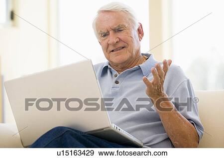 Man in living room with laptop View Large Photo Image Stock Photo - Man in living room with laptop. Fotosearch