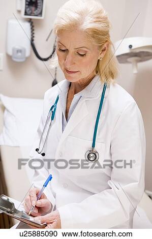 Stock Image - Middle Aged Female Doctor Writing On A Clipboard. Fotosearch