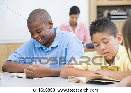 Students in class reading with teacher in background (selective focus) View Large Photo Image Stock Image - Students in class reading with teacher in background (selective focus). Fotosearch