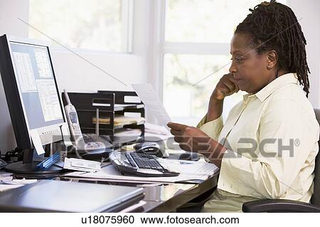 Stock Image - Woman in home office using computer. Fotosearch