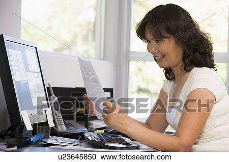 Woman in home office with computer and paperwork smiling View Large Photo Image Stock Image - Woman in home office with computer and paperwork smiling. Fotosearch