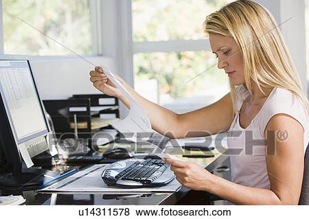Woman in home office with computer and paperwork frowning View Large Photo Image Stock Photo - Woman in home office with computer and paperwork frowning. Fotosearch
