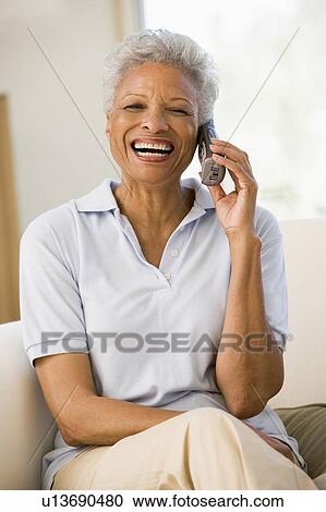 Woman sitting in living room using telephone and smiling View Large Photo Image Stock Image - Woman sitting in living room using telephone and smiling. Fotosearch