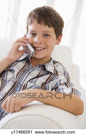 Young Boy Sitting On A Sofa Talking On A Mobile Phone View Large Photo Image Stock Image - Young Boy Sitting On A Sofa Talking On A Mobile Phone. Fotosearch