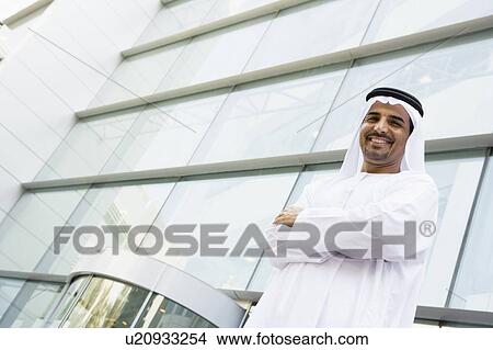 Picture - Businessman standing outdoors by building smiling. Fotosearch