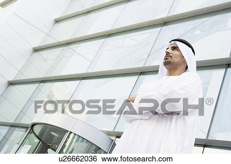 Stock Photograph - Businessman standing outdoors by building. Fotosearch