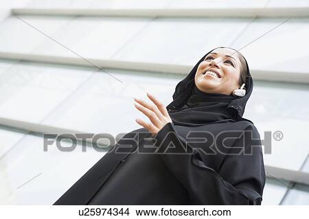 Businesswoman outdoors by building wearing headset and smiling (selective focus) View Large Photo Image Picture - Businesswoman outdoors by building wearing headset and smiling (selective focus). Fotosearch