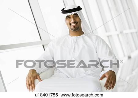 Stock Photography - Man sitting indoors smiling (high key/selective focus). Fotosearch