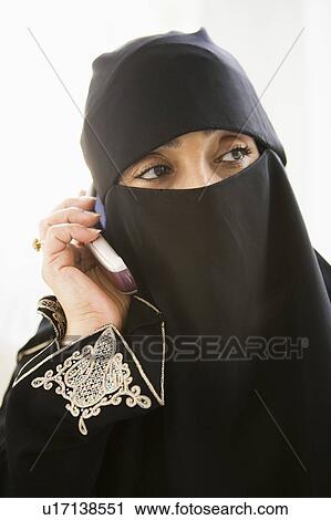 Stock Image - Woman indoors on cellular phone wearing veil (high key). Fotosearch