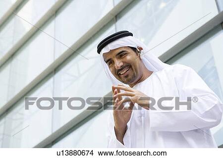 Picture - Businessman outdoors by building wearing headset and smiling. Fotosearch