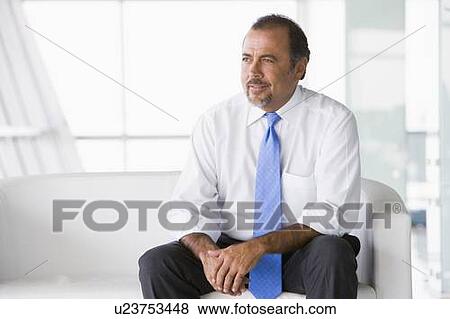 Businessman sitting indoors (high key/selective focus) View Large Photo Image Stock Photo - Businessman sitting indoors (high key/selective focus). Fotosearch