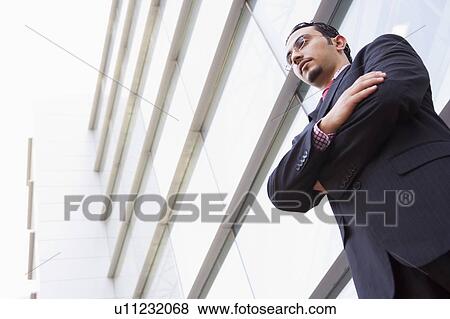Stock Photo - Businessman standing outdoors by building (high key/selective focus). Fotosearch