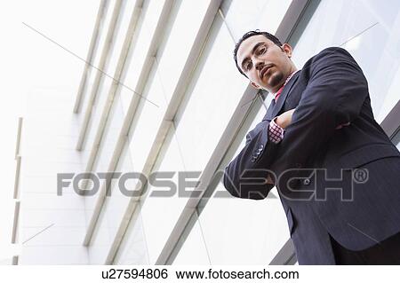 Businessman standing outdoors by building (high key/selective focus) View Large Photo Image Stock Photograph - Businessman standing outdoors by building (high key/selective focus). Fotosearch
