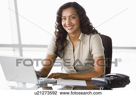 Businesswoman in office with laptop smiling (high key/selective focus) View Large Photo Image Stock Image - Businesswoman in office with laptop smiling (high key/selective focus). Fotosearch