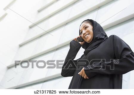 Businesswoman outdoors by building using cellular phone and smiling (selective focus) View Large Photo Image Stock Photography - Businesswoman outdoors by building using cellular phone and smiling (selective focus). Fotosearch
