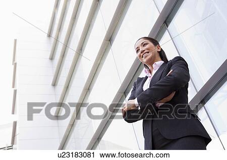 Businesswoman standing outdoors by building smiling (high key/selective focus) View Large Photo Image Stock Image - Businesswoman standing outdoors by building smiling (high key/selective focus). Fotosearch