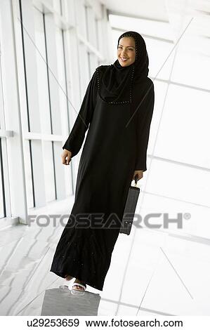Stock Photo - Businesswoman walking in a corridor with a briefcase and smiling (high key/selective focus). Fotosearch