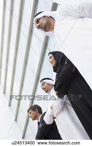 Stock Image - Four businesspeople standing outdoors by building (selective focus). Fotosearch