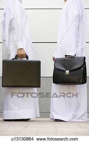 Picture - Two businessmen standing outdoors with briefcases. Fotosearch