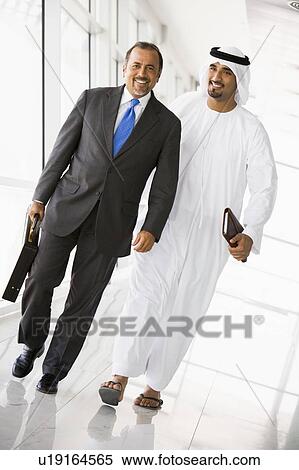 Stock Photography - Two businessmen walking in a corridor and smiling (high key/selective focus). Fotosearch