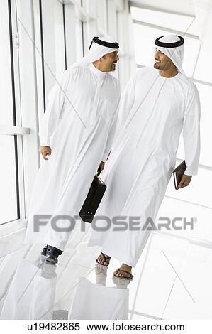 Two businessmen walking in a corridor talking and smiling (high key/selective focus) View Large Photo Image Stock Photography - Two businessmen walking in a corridor talking and smiling (high key/selective focus). Fotosearch