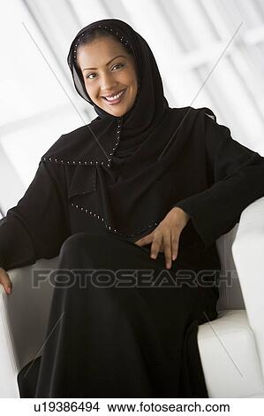 Woman sitting indoors smiling (high key/selective focus) View Large Photo Image Picture - Woman sitting indoors smiling (high key/selective focus). Fotosearch