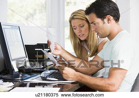 Stock Photography - Couple in home office with computer and paperwork looking unhappy. Fotosearch