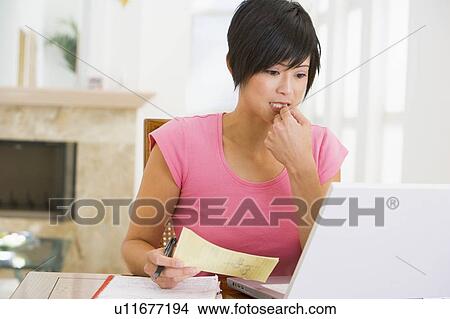 Woman in dining room with laptop thinking View Large Photo Image Picture - Woman in dining room with laptop thinking. Fotosearch
