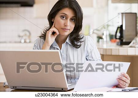 Picture - Woman in kitchen with laptop. Fotosearch