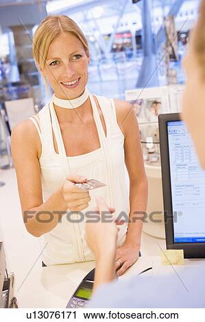 Stock Image - Woman paying for purchases with credit card. Fotosearch