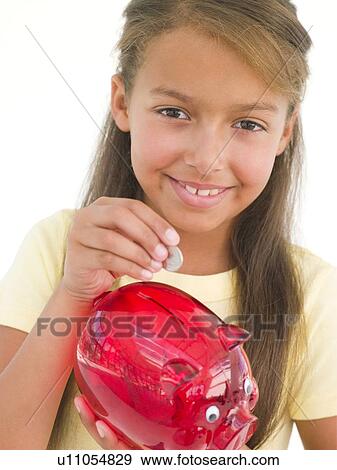 Young girl putting coin into piggy bank smiling View Large Photo Image Stock Photo - Young girl putting coin into piggy bank smiling. Fotosearch